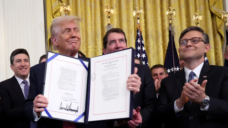Trump holding the signed GENIUS act while White house officials clap.