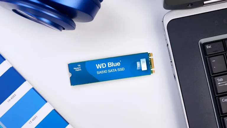 یک SSD ساتا Western Digital Blue SA510 روی میزی کنار لپ‌تاپ قرار گرفته است